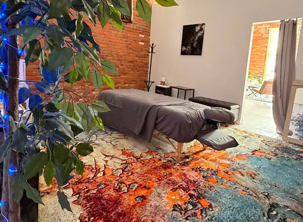 A massage table framed by greenery and exposed brick in the Serenity studio